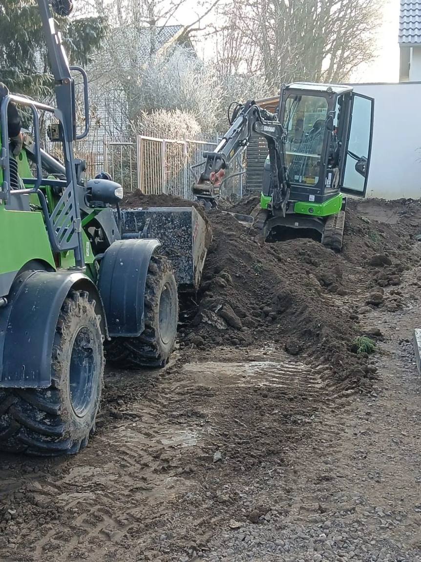 Radlader und Minibagger beim Grabenaushub im Garten