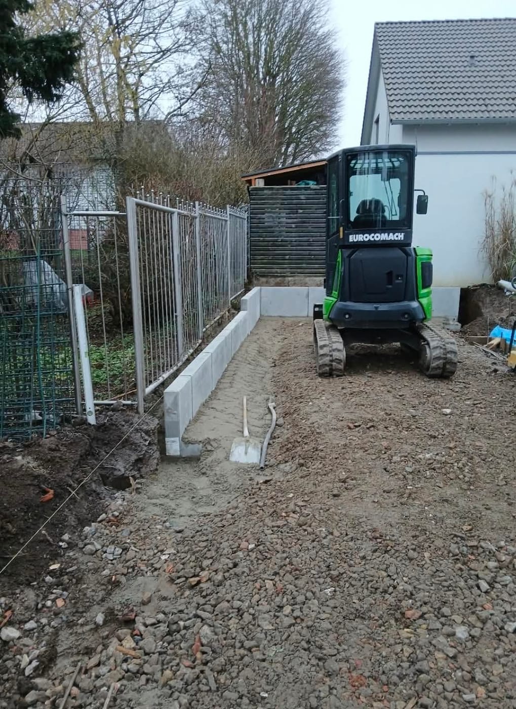 Eigener Minibagger auf einer Baustelle neben frisch gesetzten Randsteinen